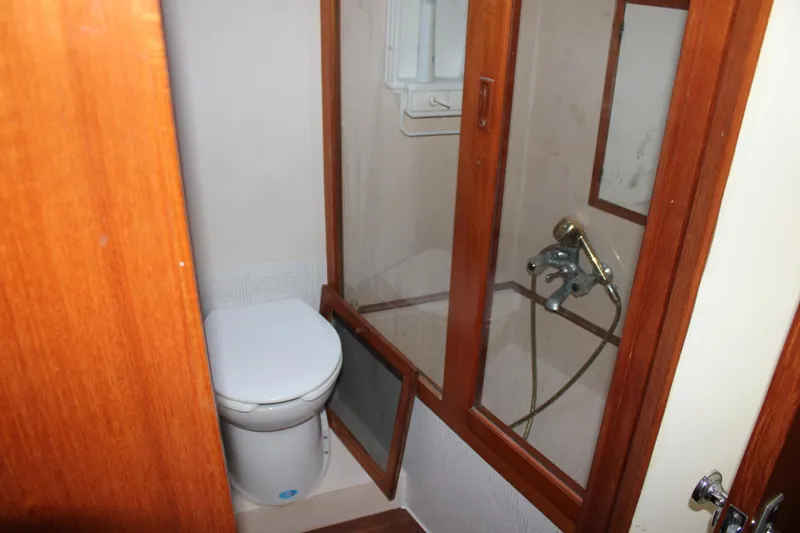 Slide: The Image of Bathroom interior of a 1994 Mikelson 64 yacht, featuring a toilet and shower. - 15