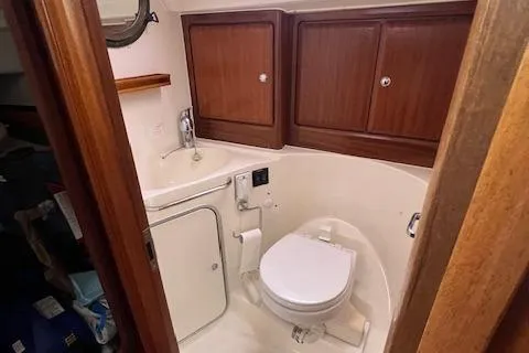 Slide: The Image of Bavaria 42 Cruiser 2000 yacht bathroom with wooden cabinets and compact toilet. - 32