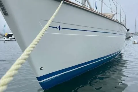 Slide: The Image of Bavaria 42 Cruiser 2000 sailboat with blue stripe, docked in calm waters. - 4