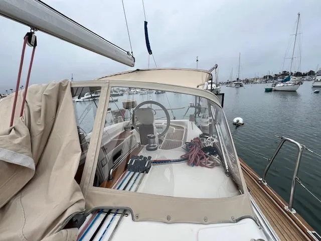 Slide: The Image of Bavaria 42 Cruiser sailboat cockpit with steering wheel, docked in a marina, overcast sky. - 44