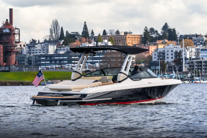 Slide: The Image of 2025 Chris-Craft Sportster 25 boat cruising on a scenic urban waterway. - 2