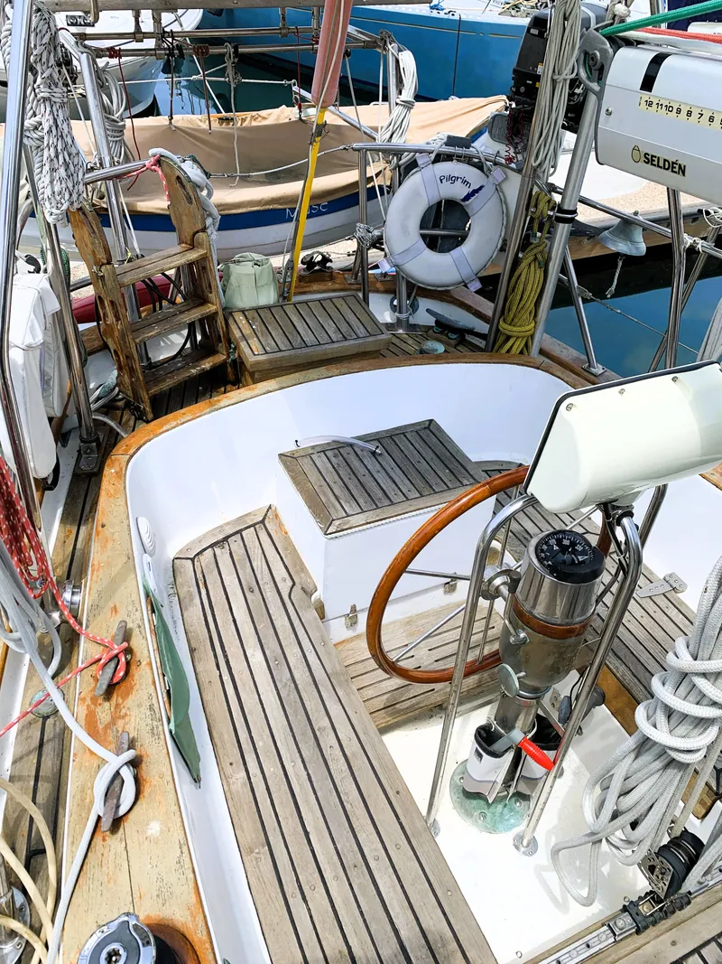 Slide: The Image of 1979 Robert Perry 41 Sloop sailboat cockpit with wooden deck and steering wheel. - 17