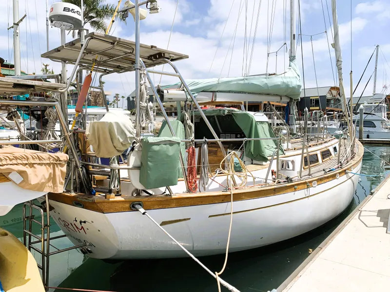 Slide: The Image of 1979 Robert Perry 41 Sloop docked at marina, featuring classic design and covered deck. - 3