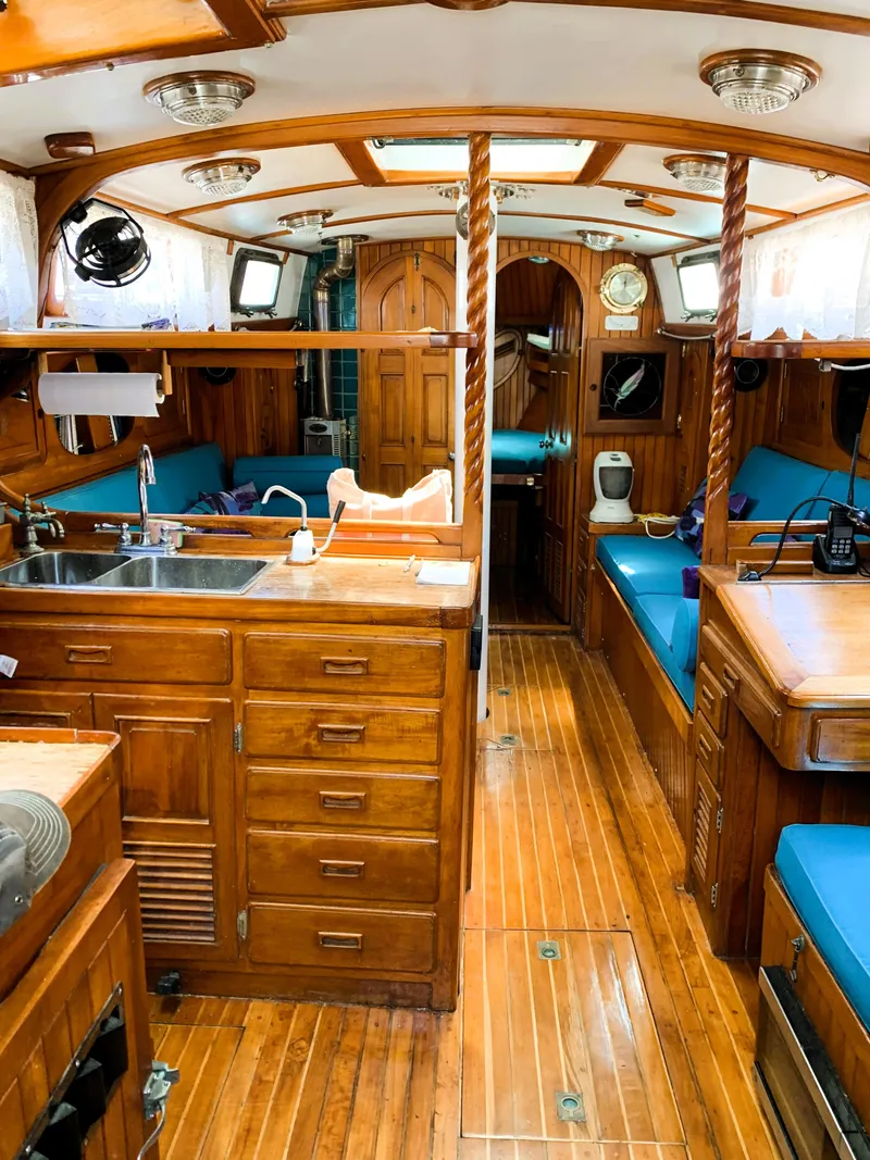 Slide: The Image of Interior of a 1979 Robert Perry 41 Sloop, featuring wooden cabinetry and blue seating. - 30