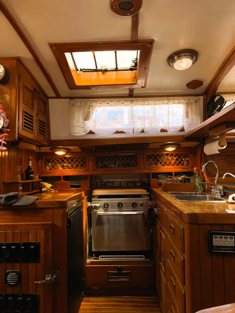 Slide: The Image of Interior of a 1979 Robert Perry 41 Sloop, featuring a cozy wooden kitchen area. - 34