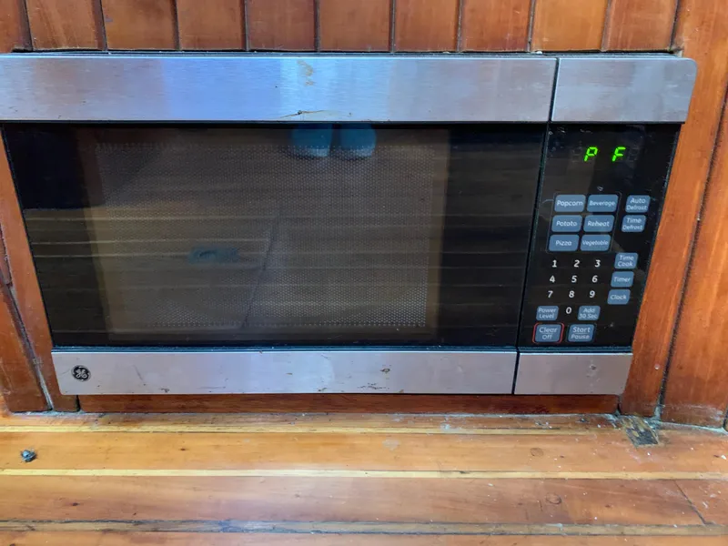 Slide: The Image of Built-in microwave on a 1979 Robert Perry 41 Sloop yacht, surrounded by wooden paneling. - 39