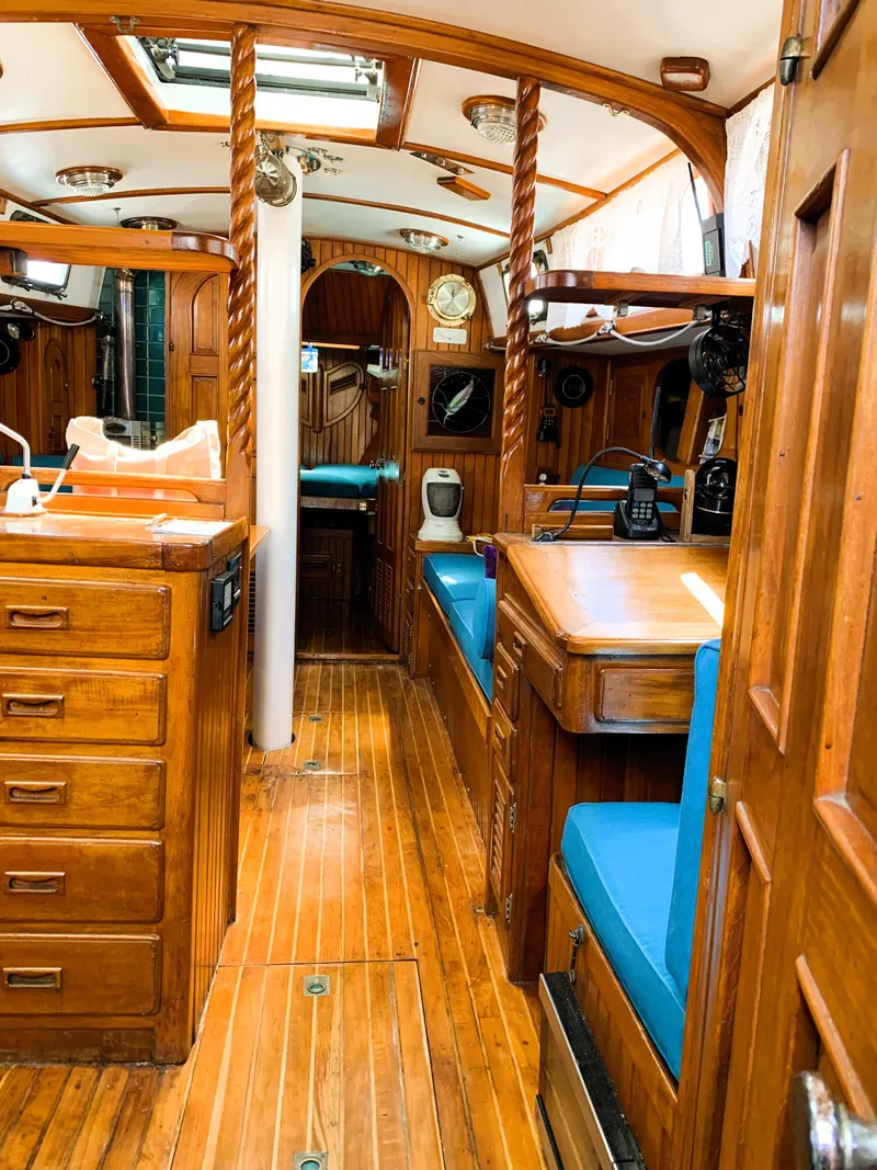 Slide: The Image of Interior of a 1979 Robert Perry 41 Sloop with wooden cabinetry and blue seating. - 44
