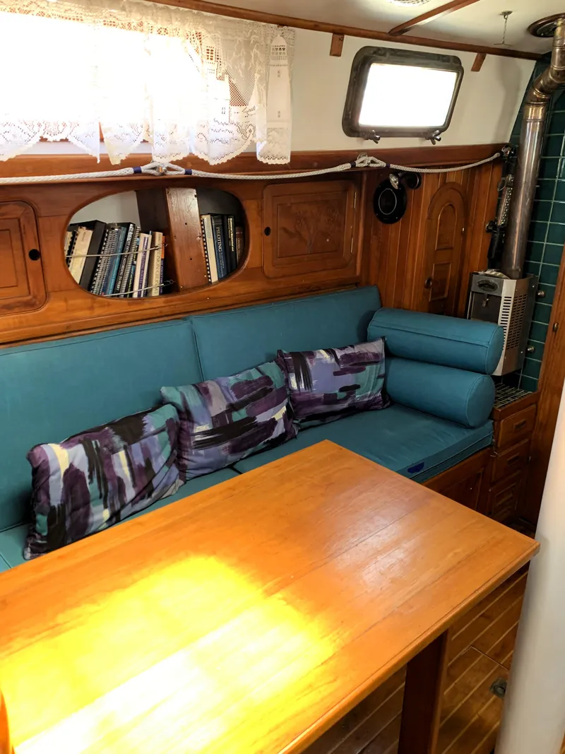 Slide: The Image of Interior of 1979 Robert Perry 41 Sloop with cozy seating and wooden table. - 46