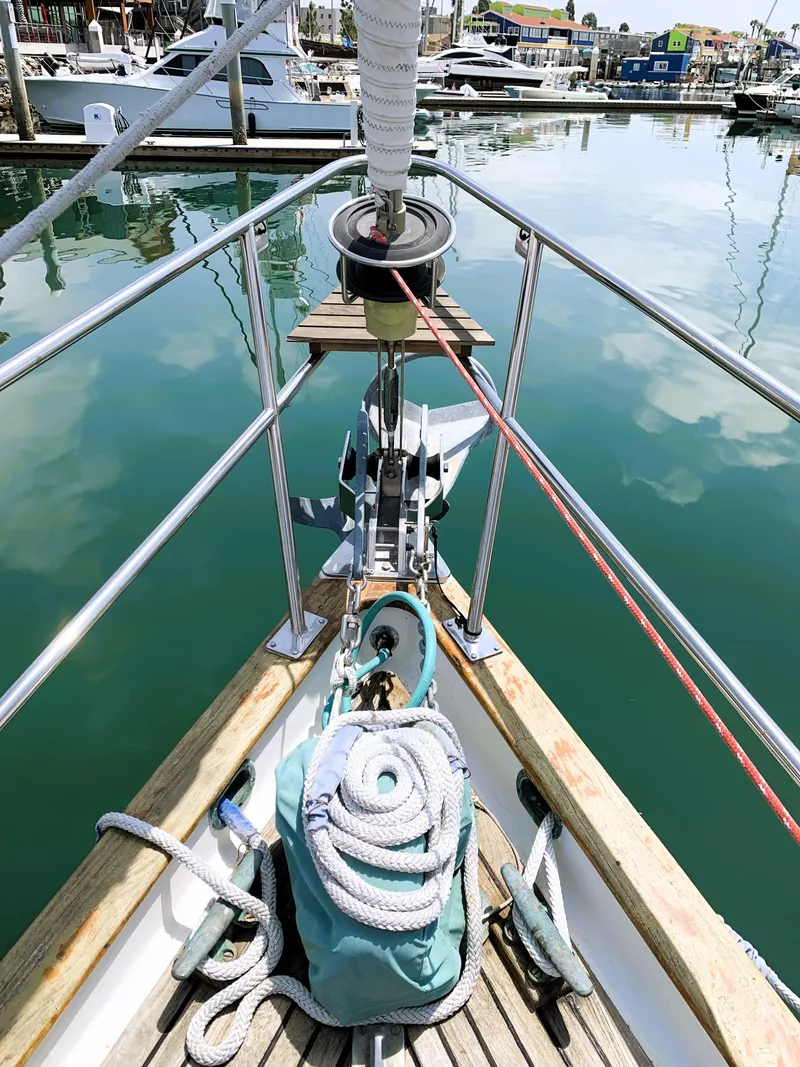 Slide: The Image of Bow of 1979 Robert Perry 41 Sloop in marina, featuring ropes and calm water reflection. - 6