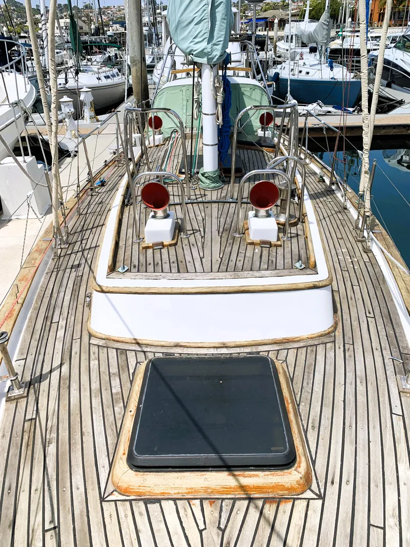 Slide: The Image of 1979 Robert Perry 41 Sloop sailboat deck with wooden finish and marina background. - 9