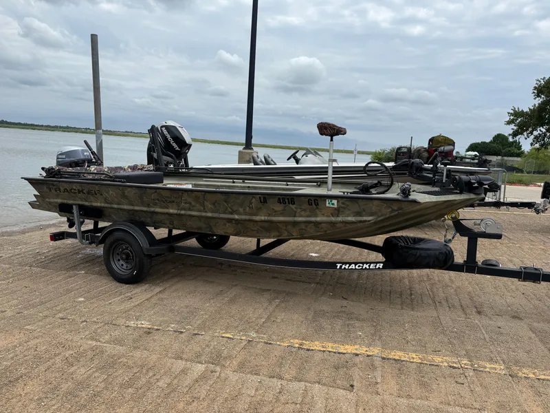 Slide: The Image of 2017 Tracker Grizzly 1654 MVX Sportsman boat on trailer by a lake. - 13