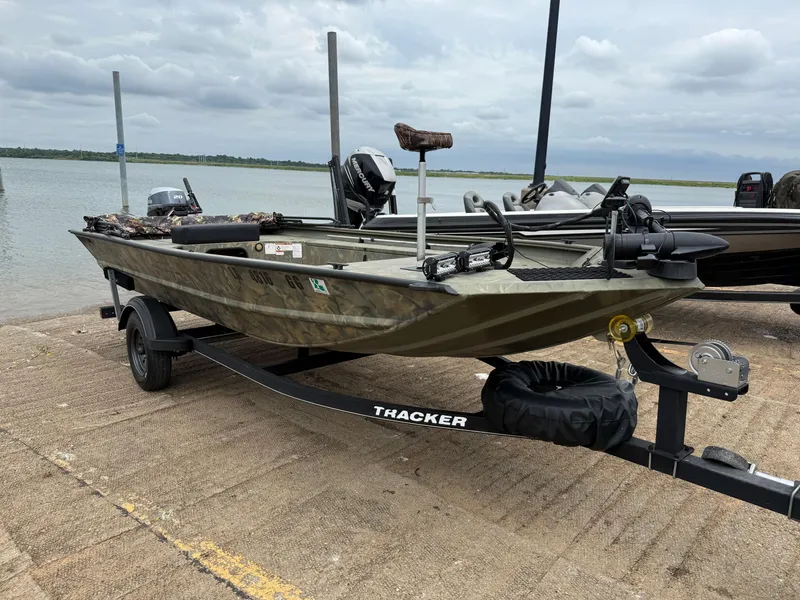Slide: The Image of 2017 Tracker Grizzly 1654 MVX Sportsman boat on trailer by a lake. - 14