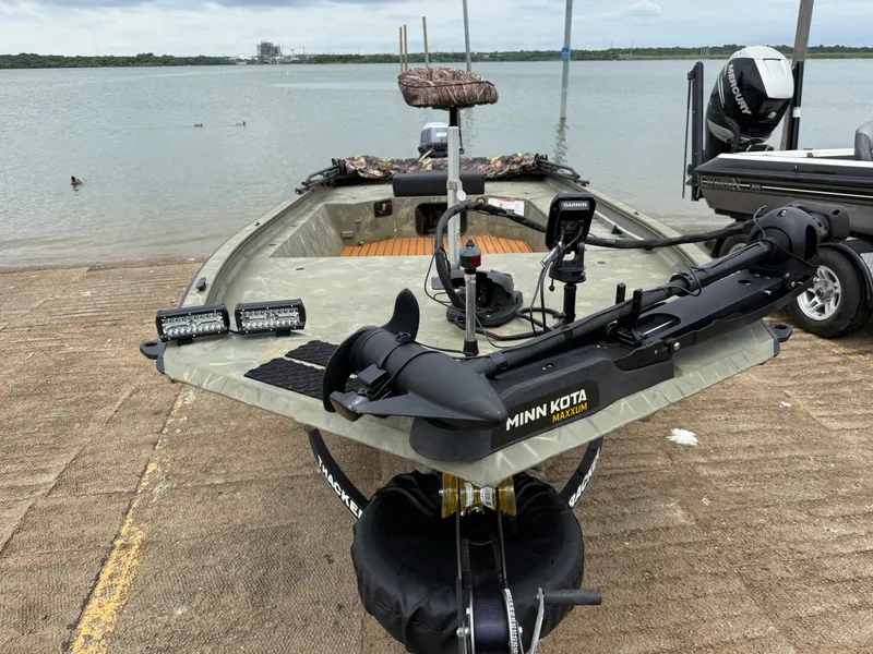 Slide: The Image of 2017 Tracker Grizzly 1654 MVX Sportsman boat with Minn Kota trolling motor by a lake. - 16