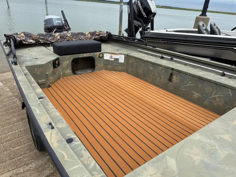 Slide: The Image of 2017 Tracker Grizzly 1654 MVX Sportsman boat with camo interior and wooden deck, docked by water. - 17