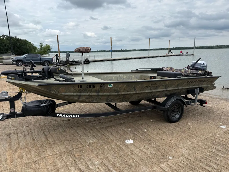 Slide: The Image of 2017 Tracker Grizzly 1654 MVX Sportsman boat on trailer by a lake. - 2