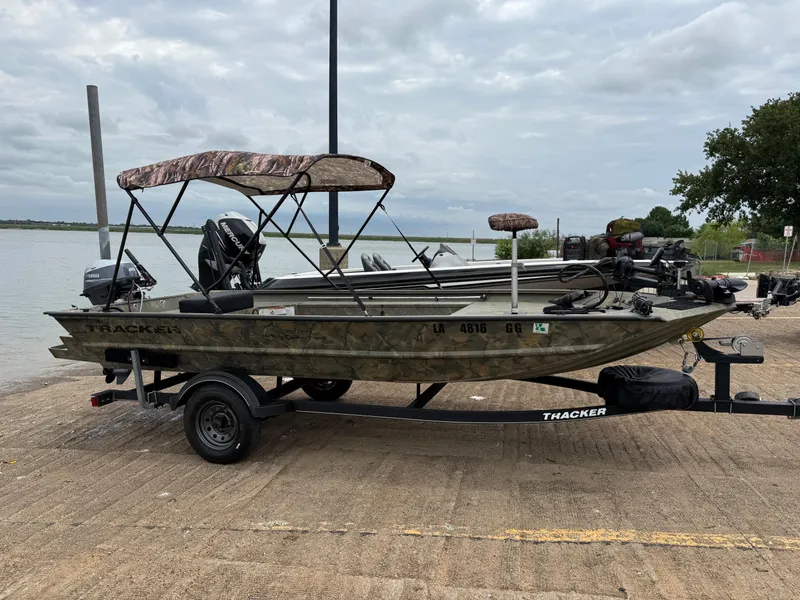 Slide: The Image of 2017 Tracker Grizzly 1654 MVX Sportsman boat on trailer by a lake. - 25