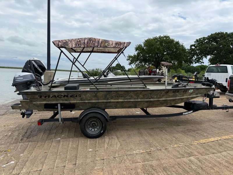 Slide: The Image of 2017 Tracker Grizzly 1654 MVX Sportsman boat on trailer by a lake. - 26