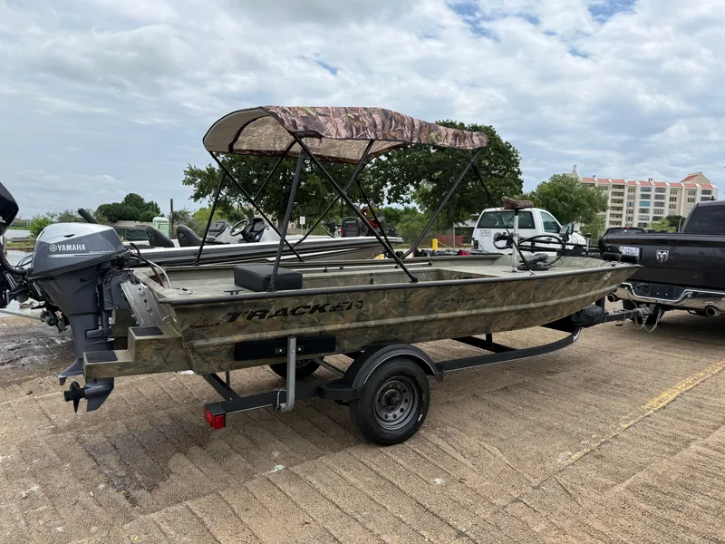 Slide: The Image of 2017 Tracker Grizzly 1654 MVX Sportsman boat on trailer, with canopy, parked outdoors. - 27