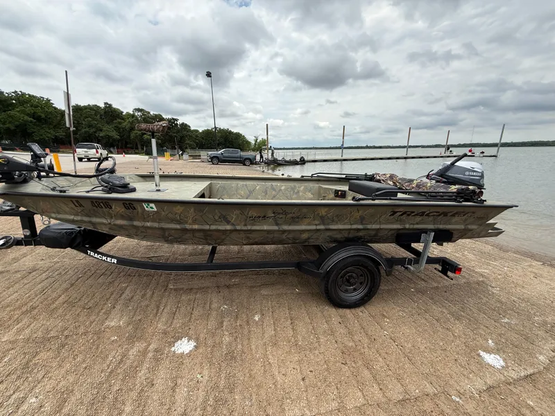Slide: The Image of 2017 Tracker Grizzly 1654 MVX Sportsman boat on trailer by a lake. - 3