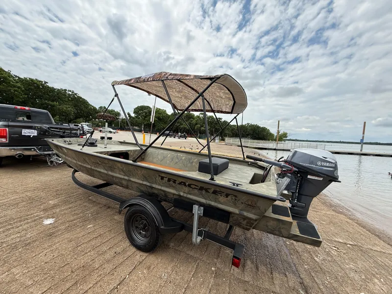 Slide: The Image of 2017 Tracker Grizzly 1654 MVX Sportsman boat on trailer by a lake. - 31