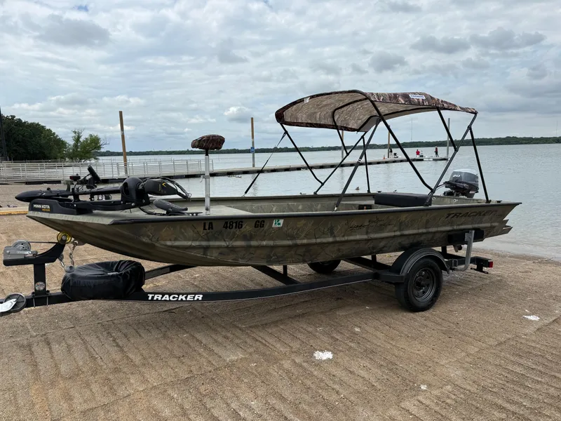 Slide: The Image of 2017 Tracker Grizzly 1654 MVX Sportsman boat on trailer by a lake. - 32
