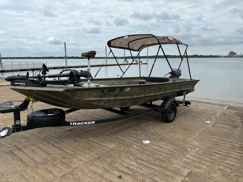 Slide: The Image of 2017 Tracker Grizzly 1654 MVX Sportsman boat on trailer by a lake. - 33