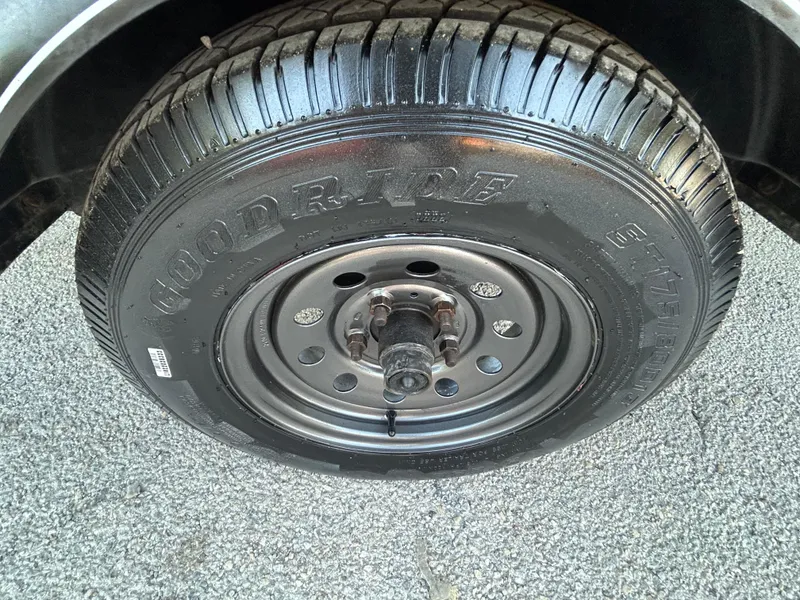 Slide: The Image of 2017 Tracker Grizzly 1654 MVX Sportsman trailer tire, Goodyear brand, on gravel surface. - 47