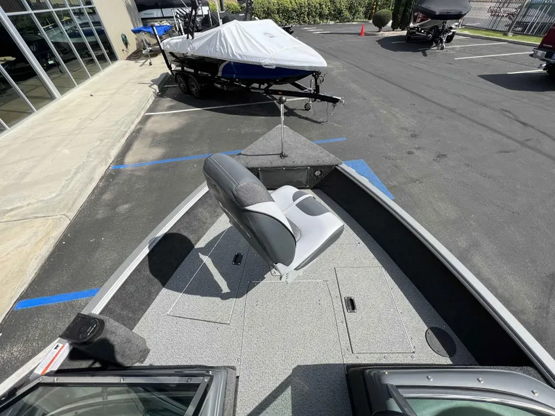 Slide: The Image of 2013 Lund 1675 Impact Sport boat interior with seating and storage, parked outdoors. - 10