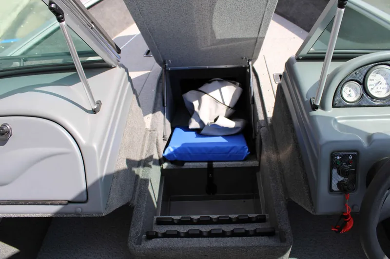 Slide: The Image of 2013 Lund 1675 Impact Sport boat interior storage compartment with blue cushion and gauges. - 12