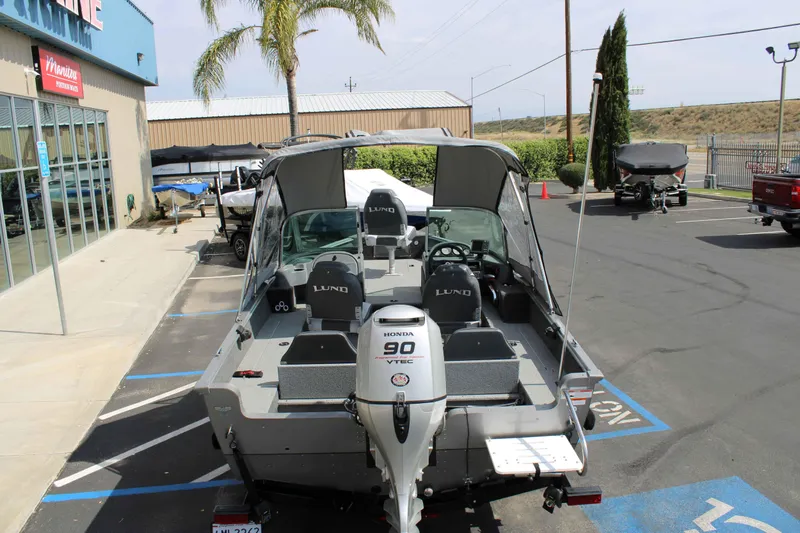 Slide: The Image of 2013 Lund 1675 Impact Sport boat with Honda 90 VTEC engine in a parking lot. - 20