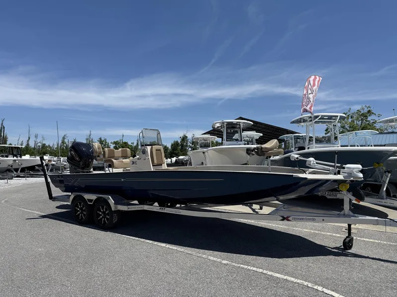 Slide: The Image of 2025 Xpress Hyper-Lift Bay Series H24 BAY boat on trailer, parked outdoors. - 1