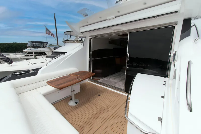 Slide: The Image of 2009 Sunseeker Predator 62 yacht with open deck, wooden table, and sliding glass doors. - 22
