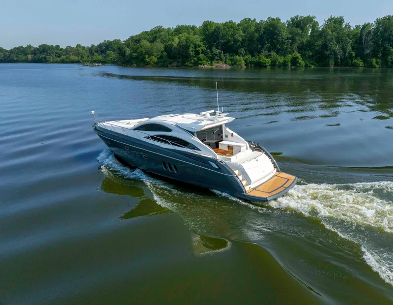 Slide: The Image of 2009 Sunseeker Predator 62 yacht cruising on a serene lake with lush green surroundings. - 8