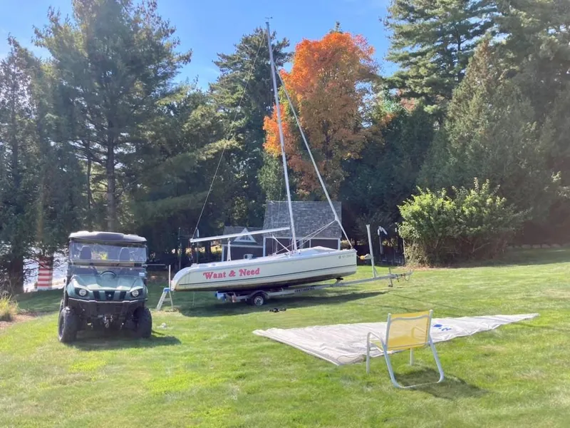 Slide: The Image of 2011 Hunter 18 sailboat on trailer, parked on grassy lawn with trees in background. - 7