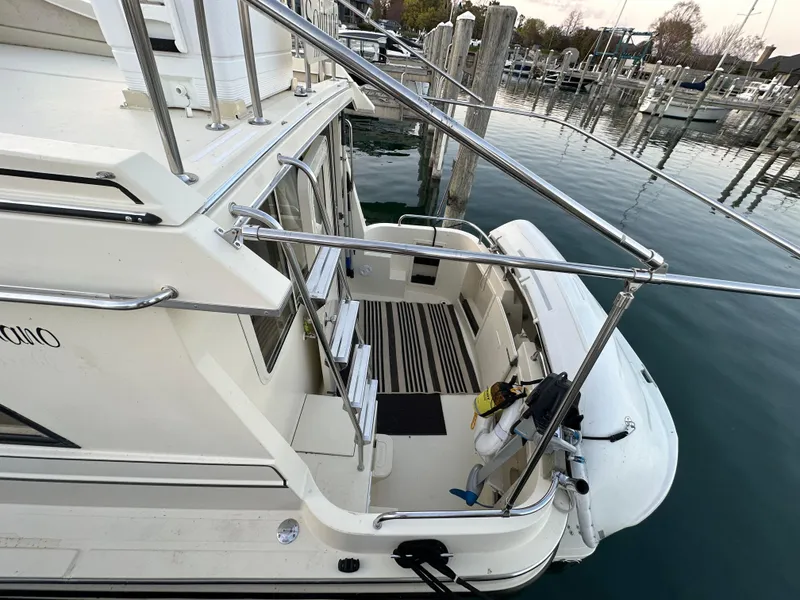 Slide: The Image of 2004 Camano Troll boat docked, featuring a spacious deck and railing, in a serene marina setting. - 14