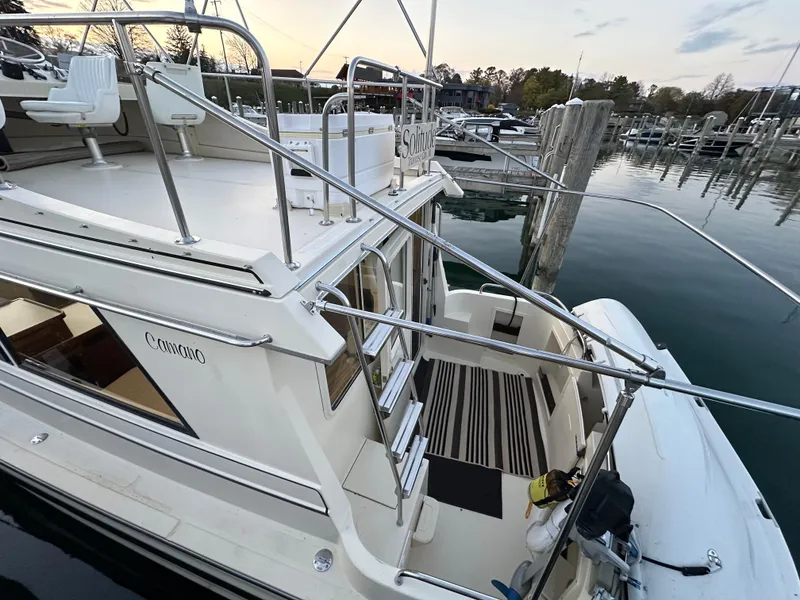 Slide: The Image of 2004 Camano Troll boat docked at marina, featuring upper deck and striped flooring. - 15