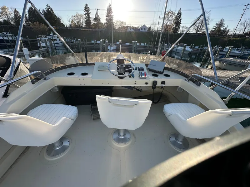 Slide: The Image of 2004 Camano Troll boat helm with three white seats and marina background. - 21