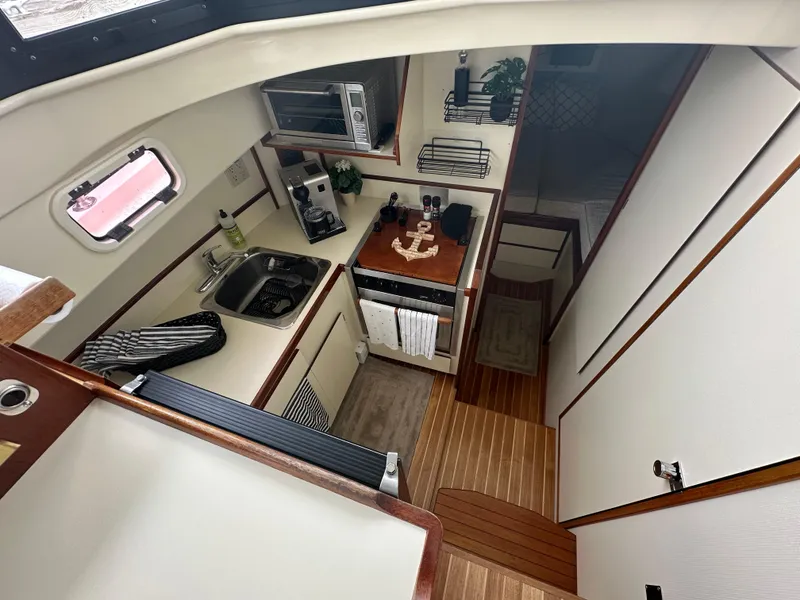Slide: The Image of 2004 Camano Troll boat interior with compact kitchen and wooden flooring. - 38