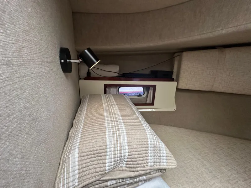 Slide: The Image of Interior cabin of a 2004 Camano Troll boat with cozy bedding and a reading lamp. - 41