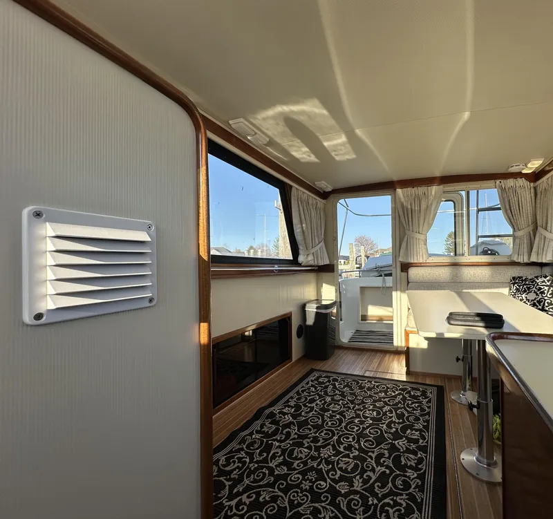 Slide: The Image of Interior of a 2004 Camano Troll boat, featuring elegant wood accents and patterned carpet. - 49