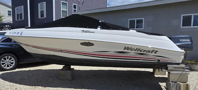Slide: The Image of 2002 Wellcraft 180 Sportsman boat on blocks, covered, beside a house. - 13