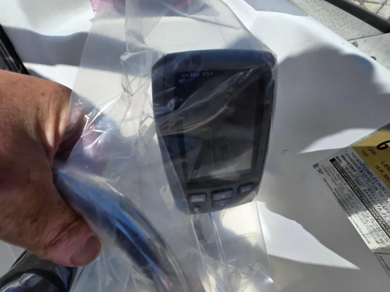 Slide: The Image of Hand holding a wrapped electronic device on a 2002 Wellcraft 180 Sportsman boat. - 16