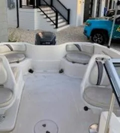 Slide: The Image of 2002 Wellcraft 180 Sportsman boat interior with seating and motor, parked near a house. - 23