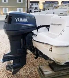 Slide: The Image of 2002 Wellcraft 180 Sportsman boat with Yamaha outboard motor, parked on gravel. - 24