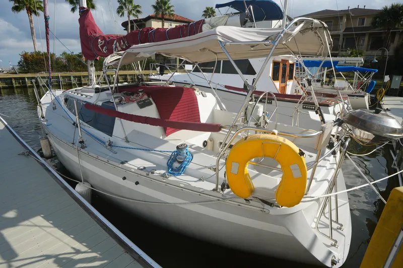 Slide: The Image of 1987 O'Day 322 sailboat docked, featuring red sail cover and yellow life preserver. - 2