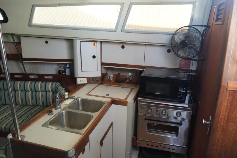 Slide: The Image of 1987 O'Day 322 yacht interior with kitchenette, featuring sink, stove, and microwave. - 20
