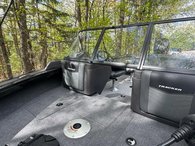 Slide: The Image of 2022 Tracker V-18 Targa boat interior with seating and windshield, surrounded by trees. - 6