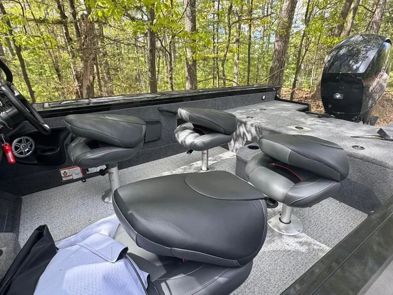 Slide: The Image of 2022 Tracker V-18 Targa boat interior with black seats and forest backdrop. - 8
