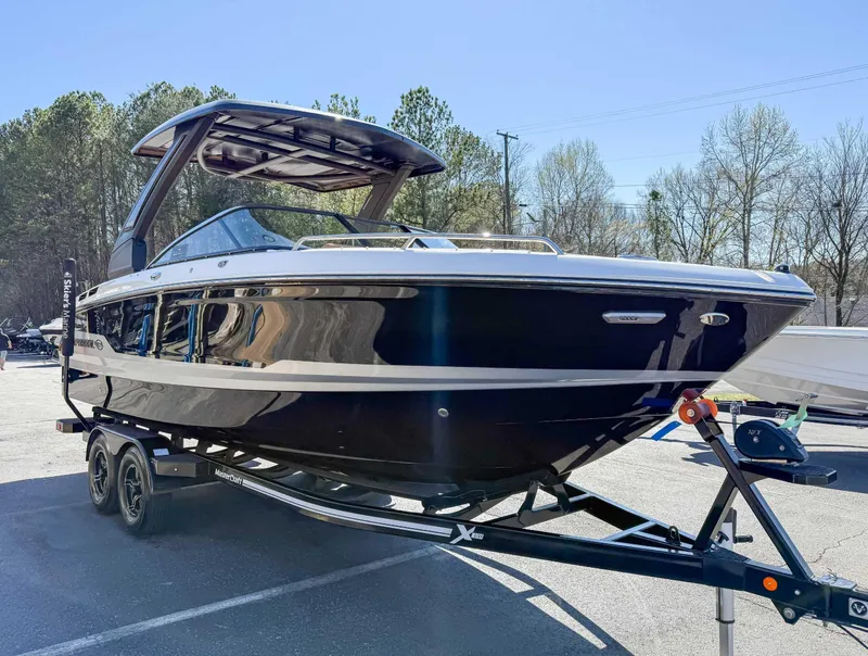 Slide: The Image of 2025 Chaparral 267 SSX boat on trailer, parked outdoors, under clear blue sky. - 5