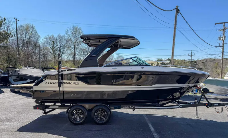 Slide: The Image of 2025 Chaparral 267 SSX boat on trailer, parked outdoors under clear blue sky. - 6
